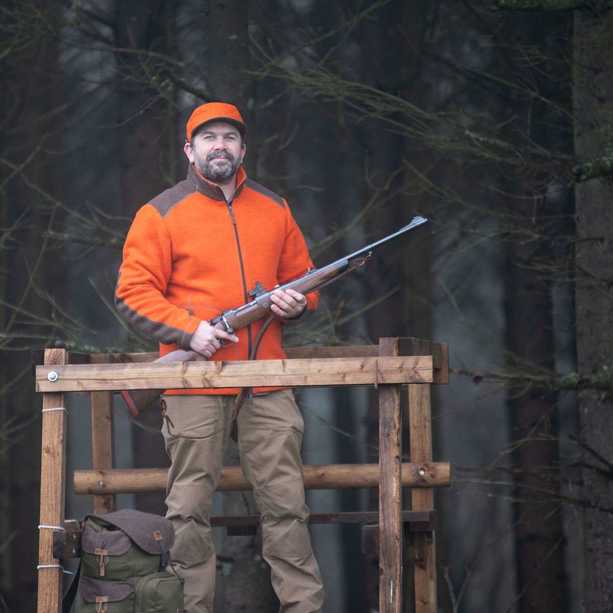 Jäger auf Hochstand in orangener Jacke