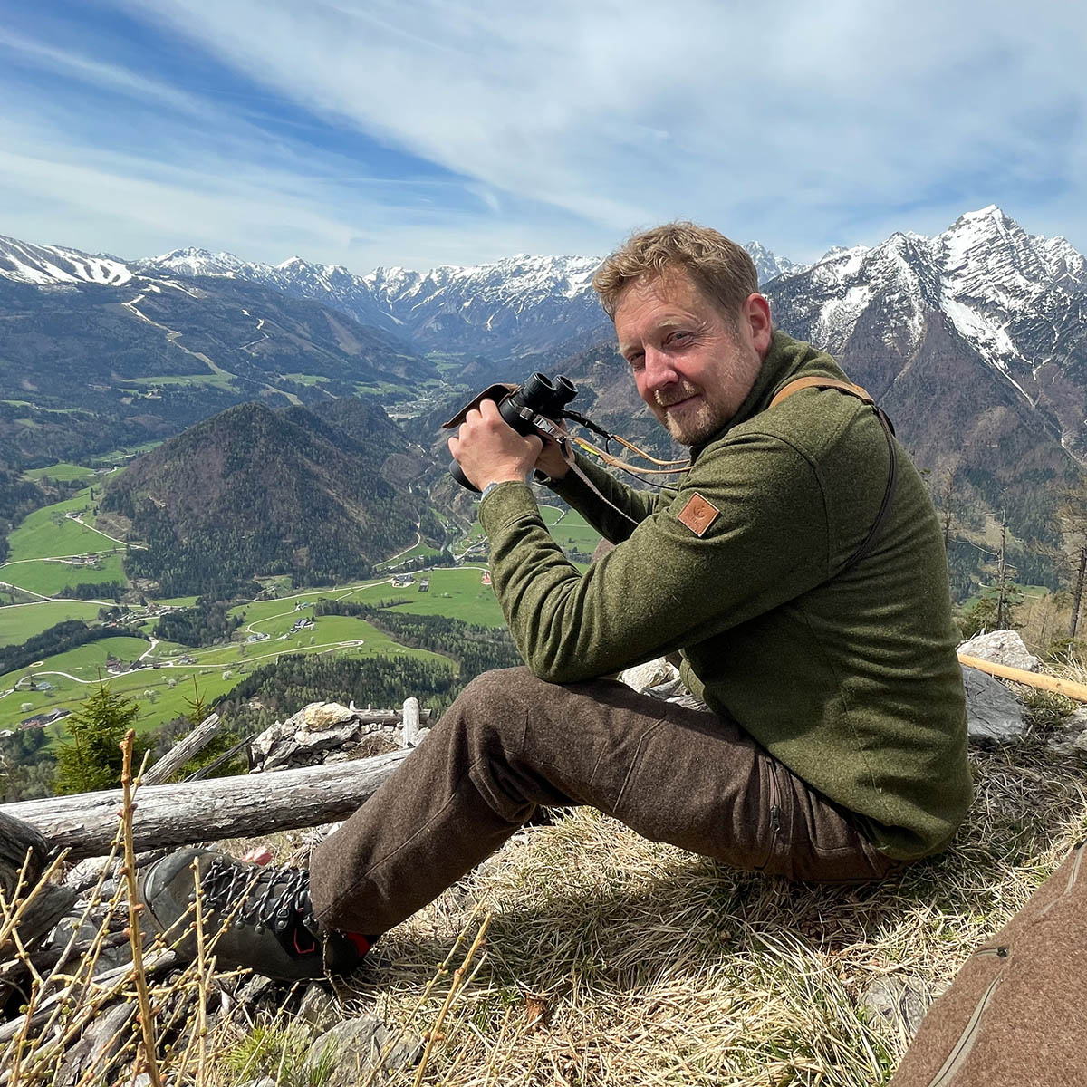 sitzender Jäger im Gebirge mit Fernglas